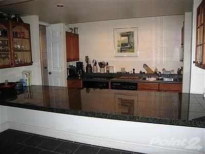 Step down kitchen with granite tile countertops, slate floors and door which leads to back deck.