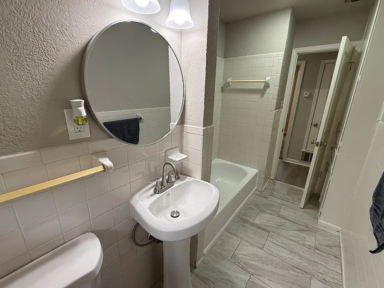 The second bath features a pedestal sink, mirror and new toilet with tile floor.