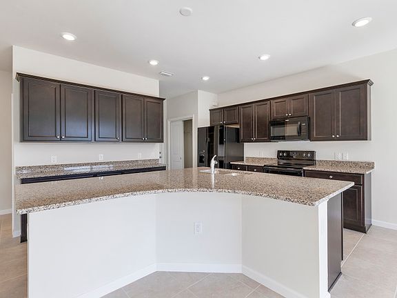 Kitchen with a large center island, granite countertops, and black appliances included