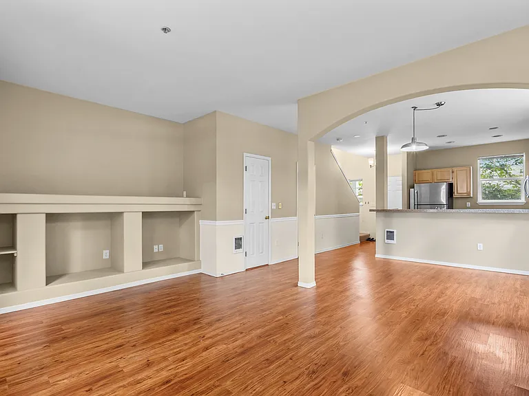 Living room and dining area. Showing the kitchen at the end. The entry door and stairs to the bedrooms showing top left.
