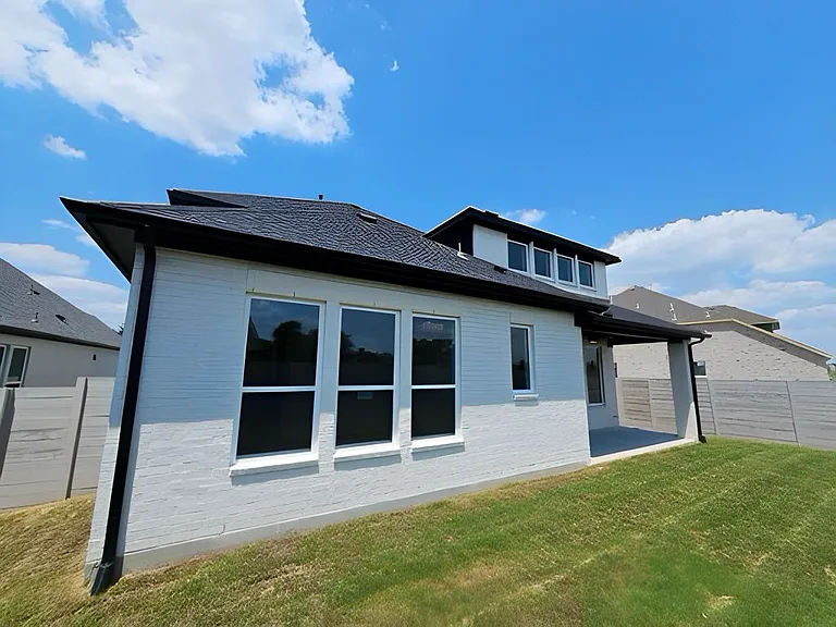 Back of property with brick siding and a patio area