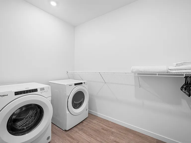 Modern laundry room featuring high-efficiency washer and dryer with ample storage space and wooden flooring. Modern laundry room featuring high-efficiency washer and dryer with ample storage space and wooden flooring.