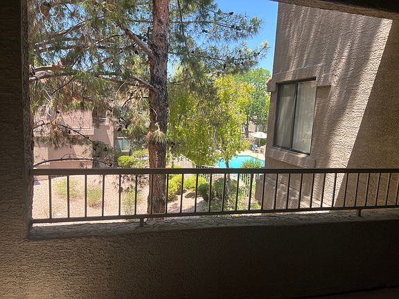 Covered patio overlooking trees and one of pools and jacuzzi in community