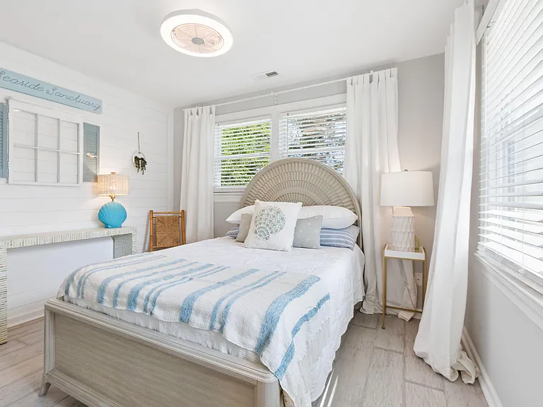 Well-appointed bedroom with a full bed, side tables, and large windows with blinds and curtains for privacy.