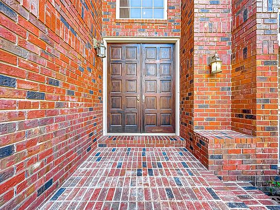 Regal entrance and porch with rich wood double paneled front door and lantern light fittings.