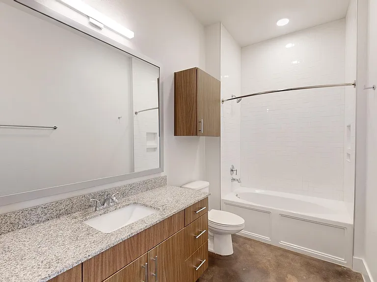 Apartment bathroom with large soaking tub and polished concrete flooring.