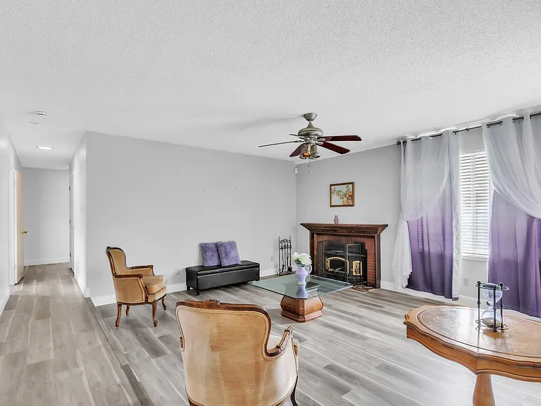 Sitting room window is facing the pool Fireplace, two sitting chairs and a bench. Ceiling fan with a light. A reading table.
