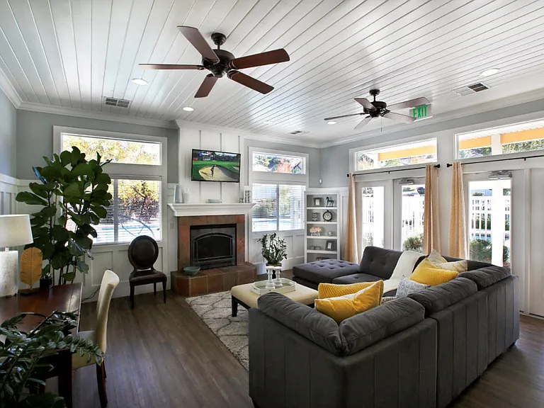 Liberty Hill Apartments, Draper, Utah, common area clubhouse with a grey couch, ceiling fan, television and fireplace.