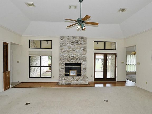 THE LIVING ROOM HAS HIGH COFFERED CEILINGS, A WOOD BURNING FIREPLACE, LOTS OF WINDOWS OVERLOOKING THE ACREAGE