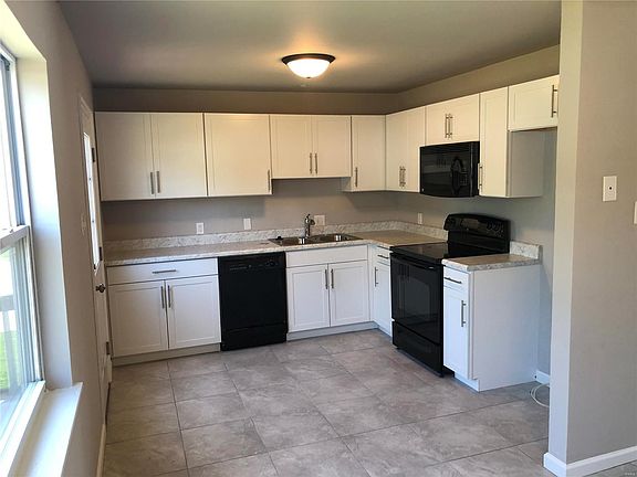 Updated kitchen with white cabinetry, countertops, cabinet hardware, sink, faucet and ceramic tile.