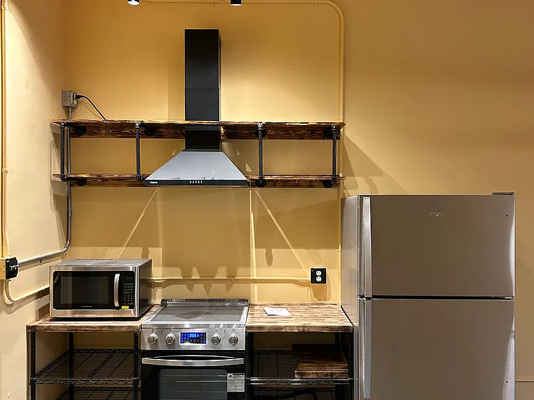 Kitchen full of light, stove and oven set, microwave, refrigerator and freezer unit, along with hood and storage space.