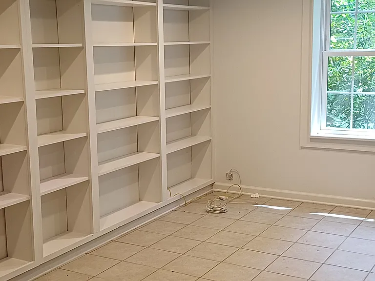Built-in bookshelves line left wall of basement den/office.