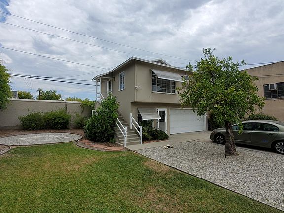 Front of unit showing grass area, patio, and orange tree.