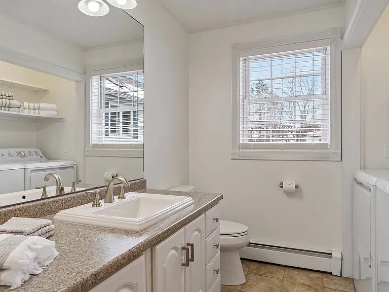 Full Bathroom, In-unit Laundry, Washer and Dryer, Vanity, Tile Flooring, Linen Storage, Neutral Colors.