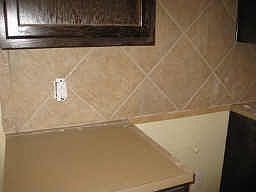 Tile included on the kitchen floor, and on the backsplash. Laminate countertop included.. still time