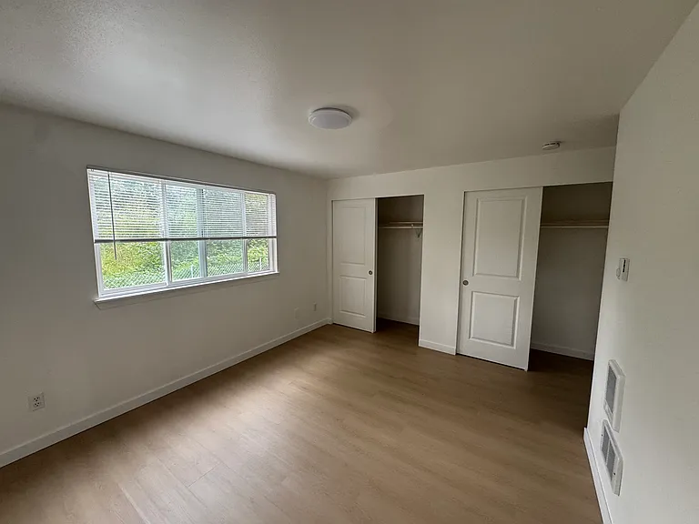 Bright primary bedroom with two large closets, new hard-surface flooring, and plenty of space for a king-size bed.