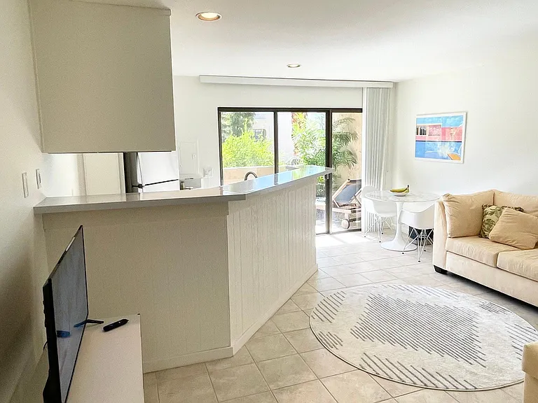 Bright, open concept kitchen and living space. Large glass sliding door to the balcony. West facing view overlooking Mount San Jacinto and peek-a-boo of The Hope Residence. Vertical blinds are installed.