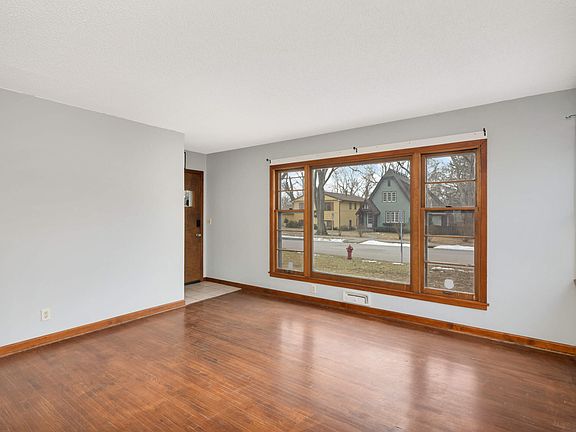 Front living room with several windows, hardwood floors and newly painted walls.