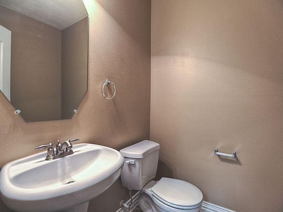 Spacious powder room with neutral colors and pedestal sink directly off of downstairs office