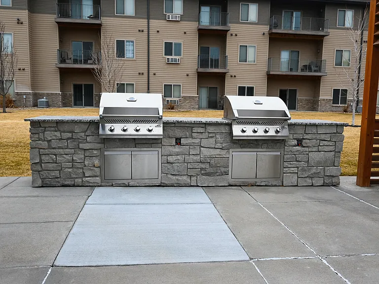 Two BBQ grills are in front of apartment buildings at The Sterling Kearney.