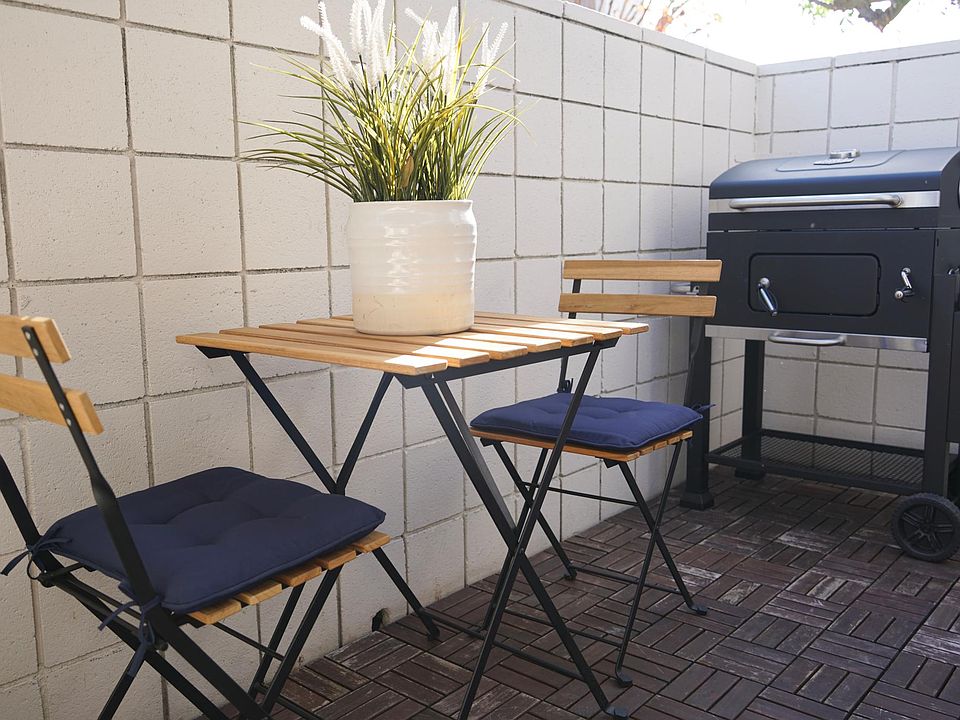 Gorgeous patio with durable deck, sofa, umbrella, seats, a table, and a grill.