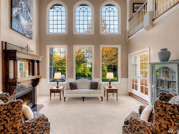 Thoughtful design went into this formal living area- stunning fireplace mantel  centered in the middle of this entertaining room and picturesque 2 story windows overlooking the private sprawling backyard.