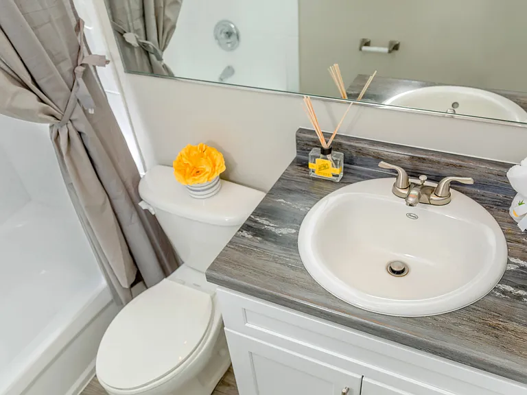 Newly remodeled bathrooms offering a refreshing escape with contemporary design - featuring black-fusion countertops, large mirrors, and wood-style flooring.