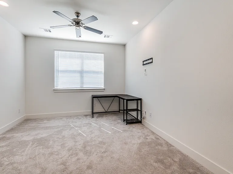 Master bedroom with ceiling fan and lots of natural sunlight (desk has been removed.)