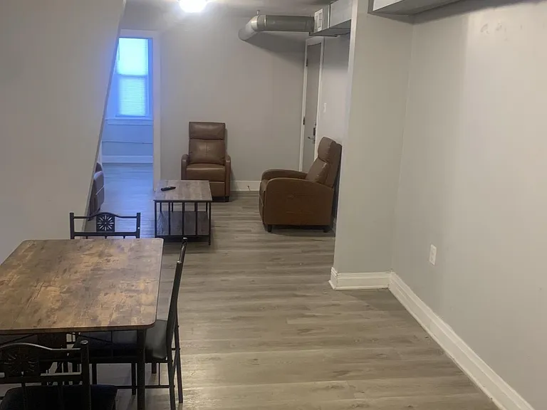 Open common area with dining table and lounge seating, plus durable flooring and a window for natural light.