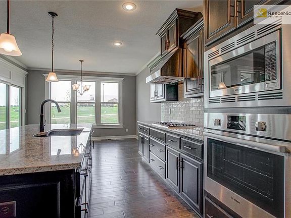 This kitchen has stainless steel Bosch appliances, custom cabinetry, soft-close drawers, gas cooktop, granite counters, a huge island and is open to the dining area and great room. Notice the sliding door access to the covered patio.
