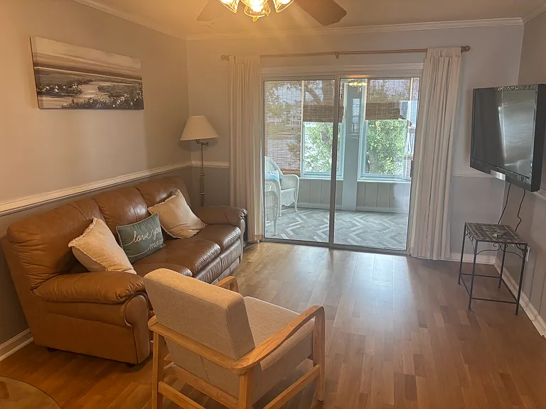 Living room full view; comes with couch, chair, wall mounted TV and small table