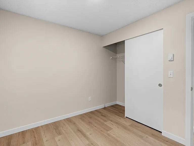 A flexible second bedroom with wood-style flooring, neutral finishes, and convenient built-in closet storage. A flexible second bedroom with wood-style flooring, neutral finishes, and convenient built-in closet storage.