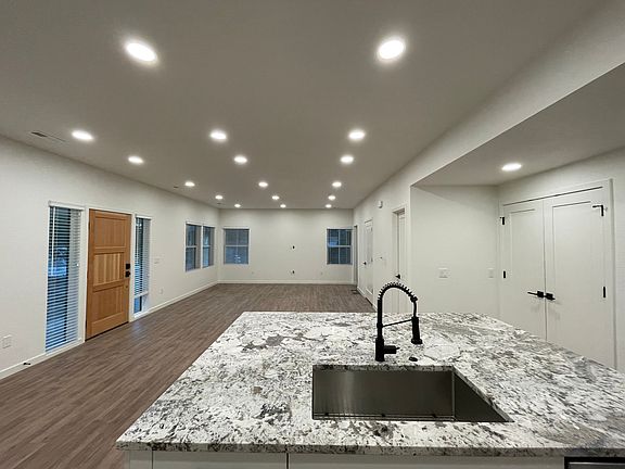 Looking over the kitchen Island, which is open to living area. Front door is on left of picture, with floor to ceiling sidelight windows. Large double door pantry (where you see the black hinges and handles to the right of the island).