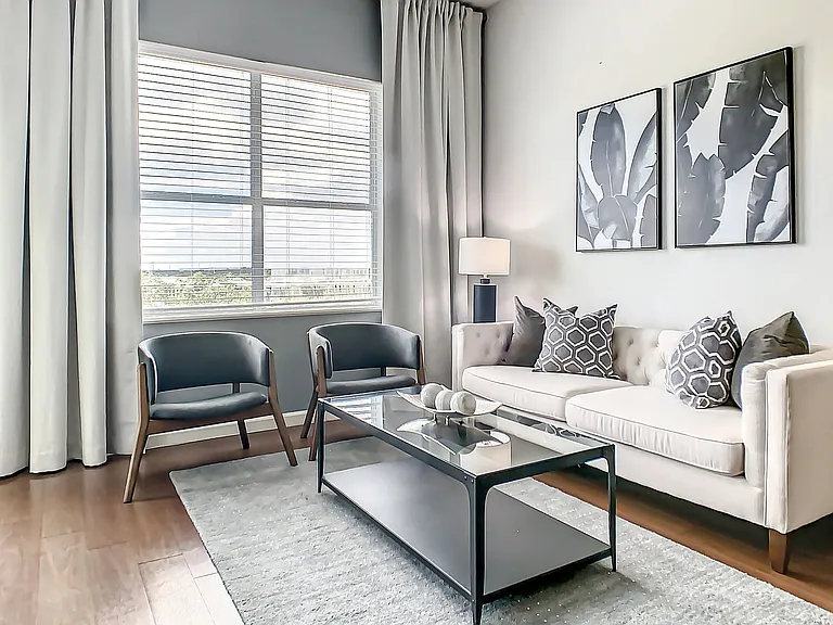 Bask in our spacious living room's classic comfort, adorned with wood-style flooring and large windows, welcoming in ample natural light.
