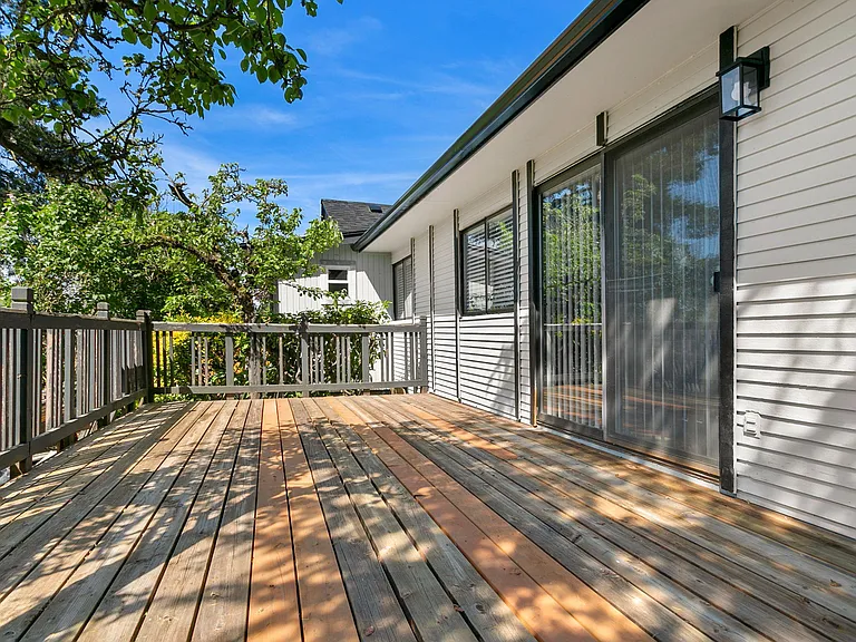 Private wooden deck with railing and sliding glass door access, offering space to relax or dine outdoors.