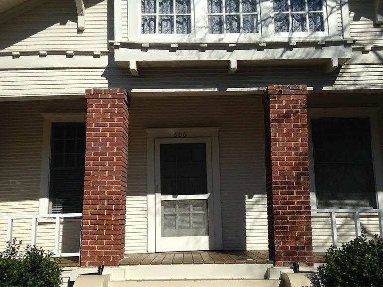 View of lovely front porch with large outdoor space for entertainment and gatherings. Lovely landscaped yard and lighting surrounds house.