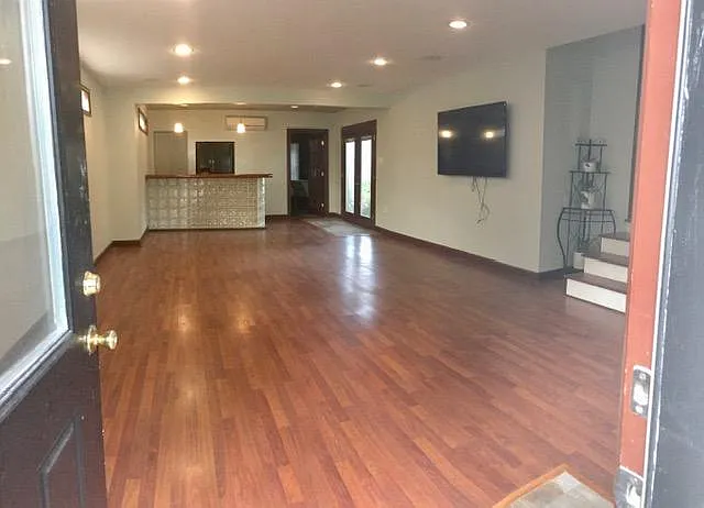 Large bonus room. (New tile flooring, replacing engineered wood floors, are not shown in photograph.) Dry bar, side-by-side refrigerator, French doors overlooking back yard, storage room in rear.