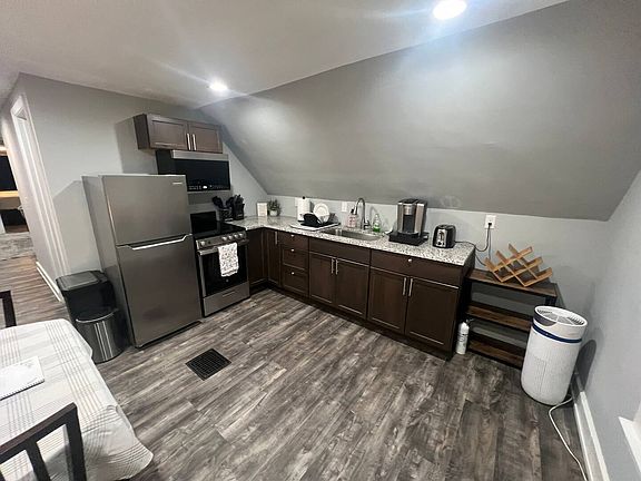 Kitchen with table, fridge & freezer, electric range with oven, Keurig coffee maker, toaster, and microwave.