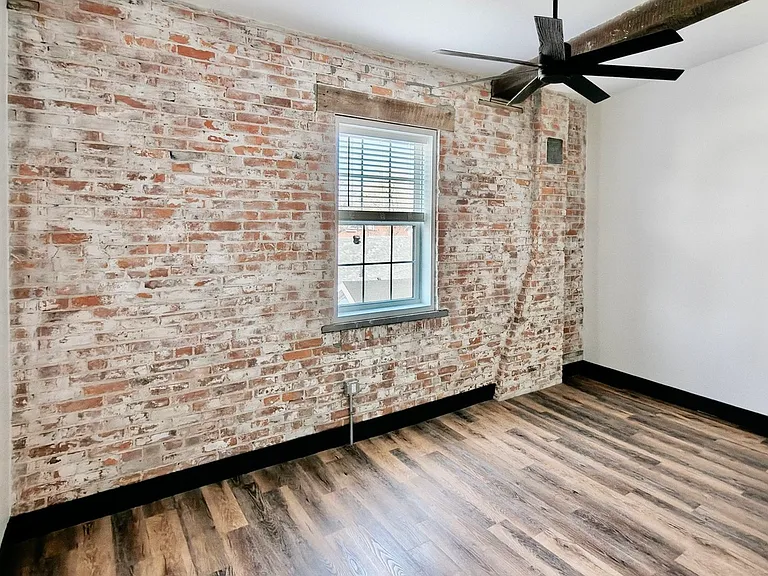 Primary bedroom features original brick and beams. Room has its own bathroom and a walk in closet
