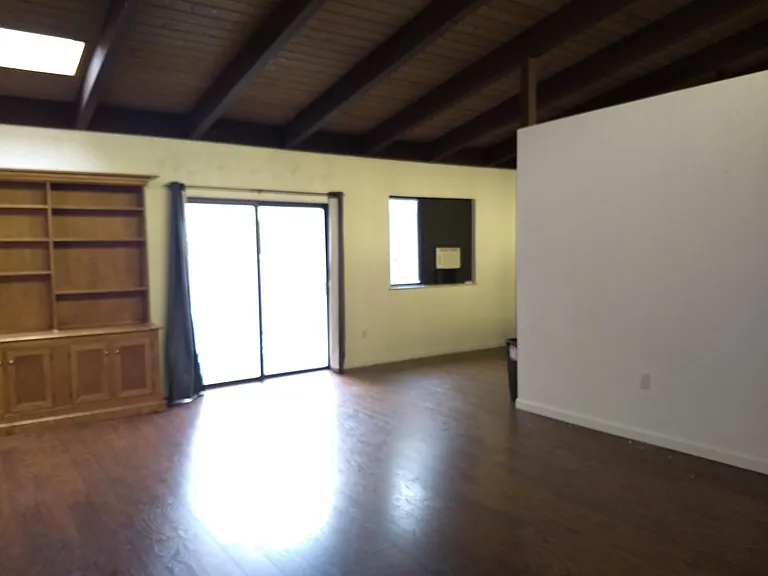 Main Living room with vaulted ceilings and sliding glass door to back enclosed deck