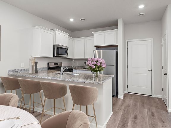 The kitchen has sprawling granite countertops and stainless steel appliances and plank flooring.