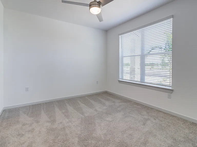 Plush carpet, abundant natural light from a large window, a ceiling with overhead lighting, and plenty of outlets proves a restful, move-in-ready retreat.