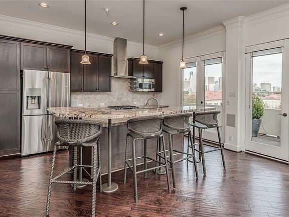 Kitchen features dark cabinets, GAS COOKING, exotic granite, island with elevated wrap around creating Breakfast Bar, and SS appliances including warming drawer! Note how the balcony is just an extension of the LR/DR/Kitchen and look at those Downtow