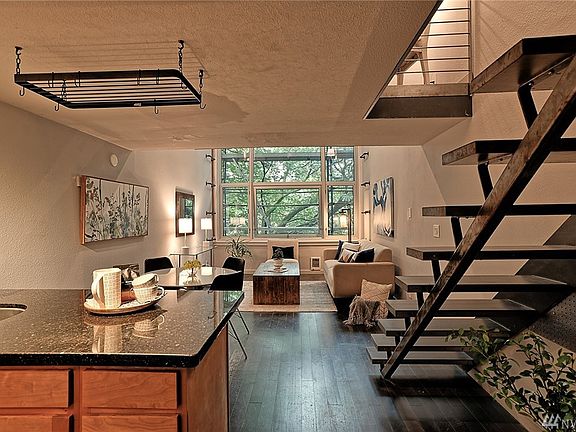 Looking from living room back to kitchen, front door, staircase and loft.