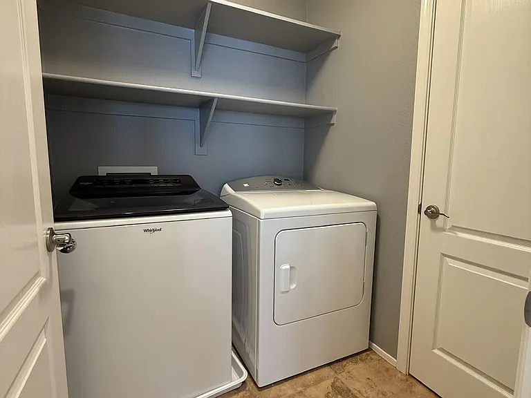 Full-size laundry room including ample storage shelves, closet and washer and dryer.
