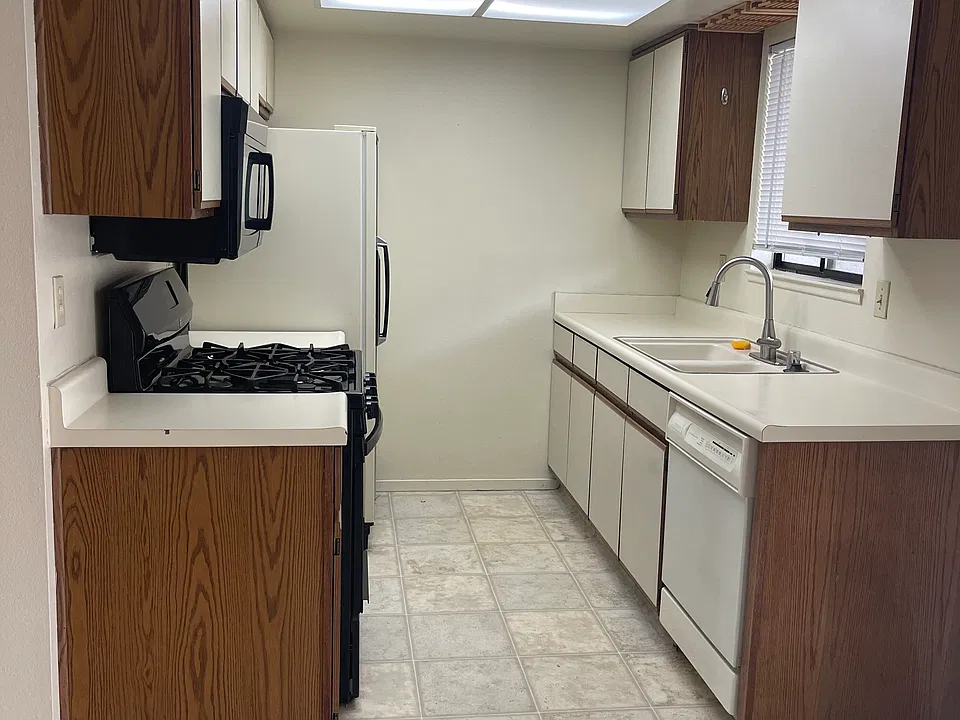 Galley kitchen with gas range, microwave, dishwasher, refrigerator.