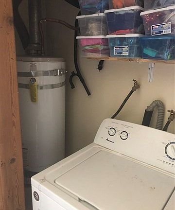 Indoor laundry/water heater. Water heater on gas. Drier on Electric. Storage shelves above.