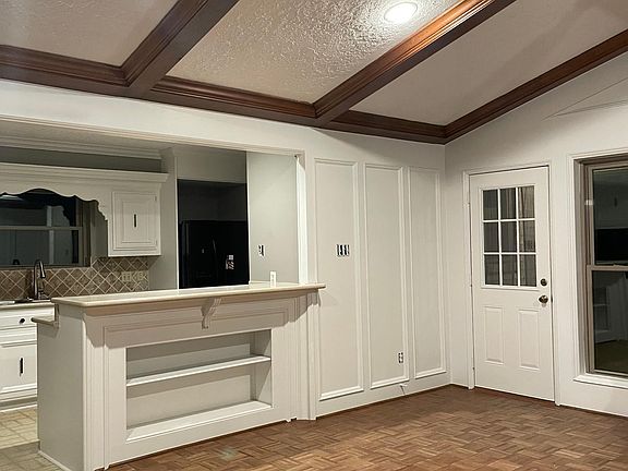 Large den with wood floors, fireplace, built in shelves, and exposed wooden beams.