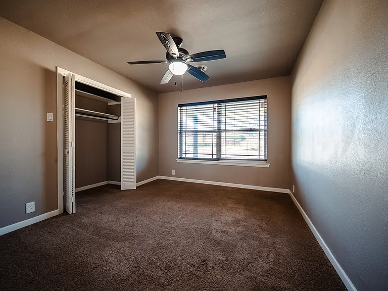 Second bedroom with ceiling fan, carpeted floors, and window blinds