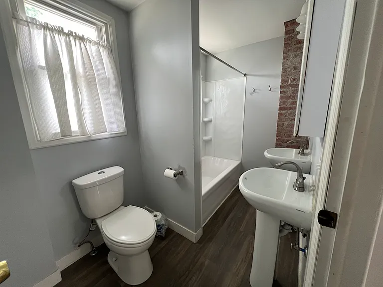 Bathroom with new sinks, lightings, medicine cabinets & exposed brick.